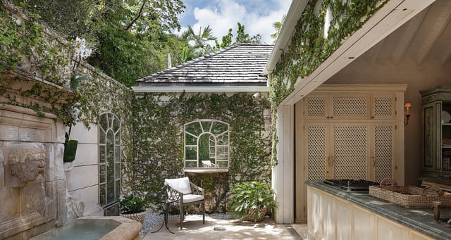Terrace with seating area and a stone fountain against a wall at Villa Bon Temps, Pointe Milou